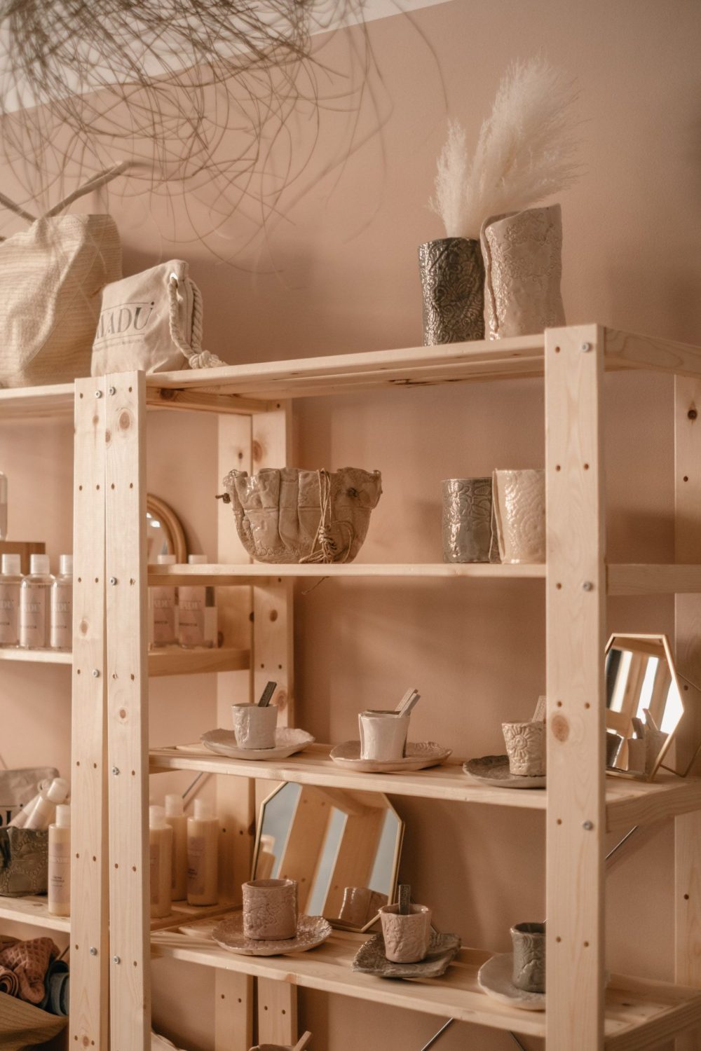 The photo shows InTerra ceramics displayed on a natural wood shelf at Spazio Vayadù, the concept store near the Budello in Alassio