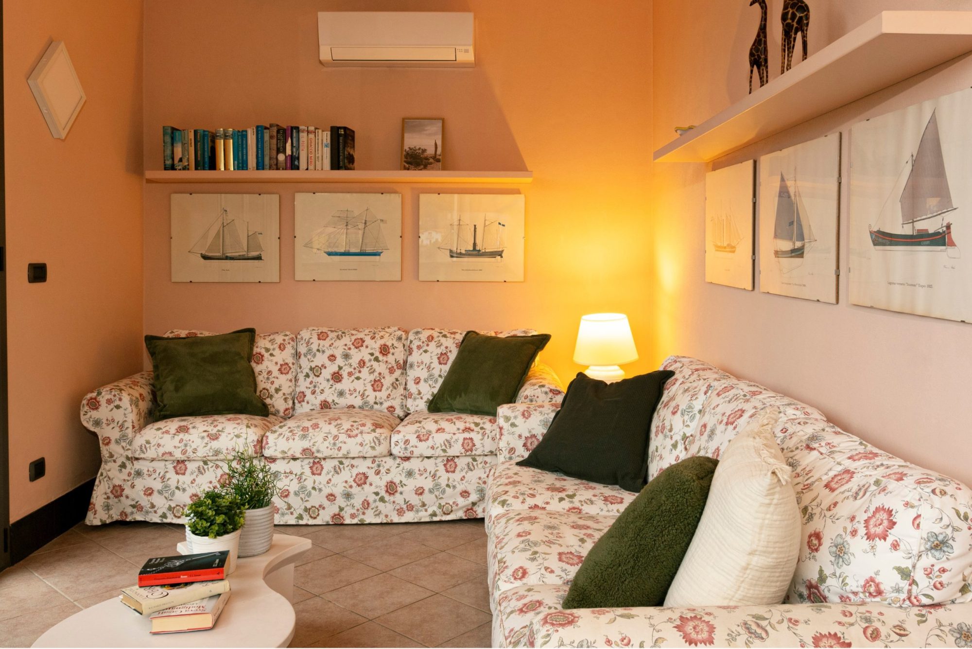 The living room with white, flower-patterned sofas arranged in a corner in the Casa Armonia villa with garden.