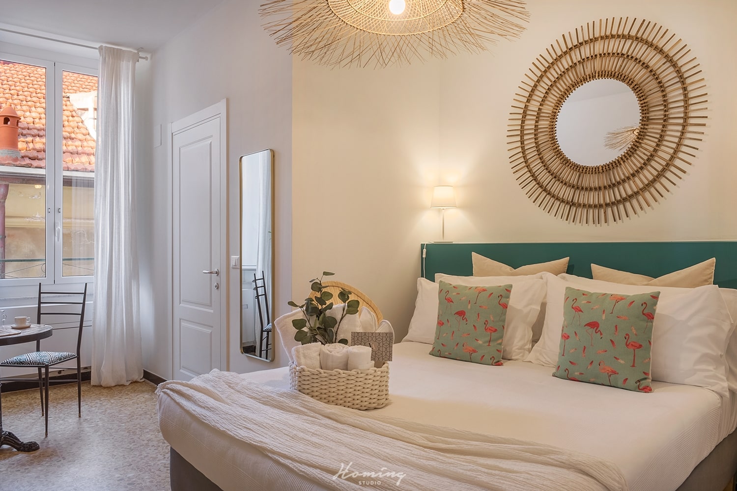 The double bed in the Coppelia room with a window overlooking Alassio, surmounted by a large straw mirror